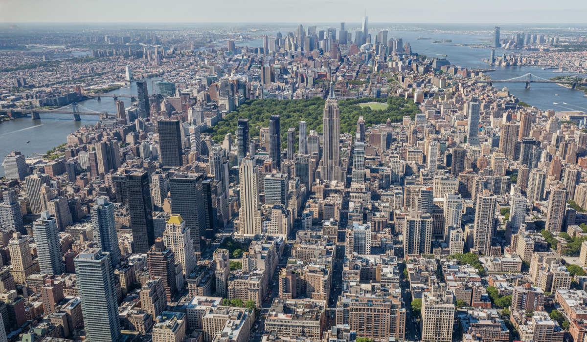 Aerial skyline of Manhattan with Central Park centered and surrounding rivers and bridges in view.